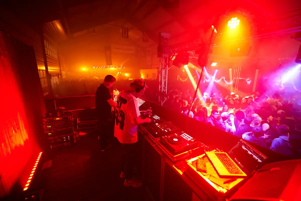 Blick vom DJ-Pult über die Menge, rotes und blaues Partylicht