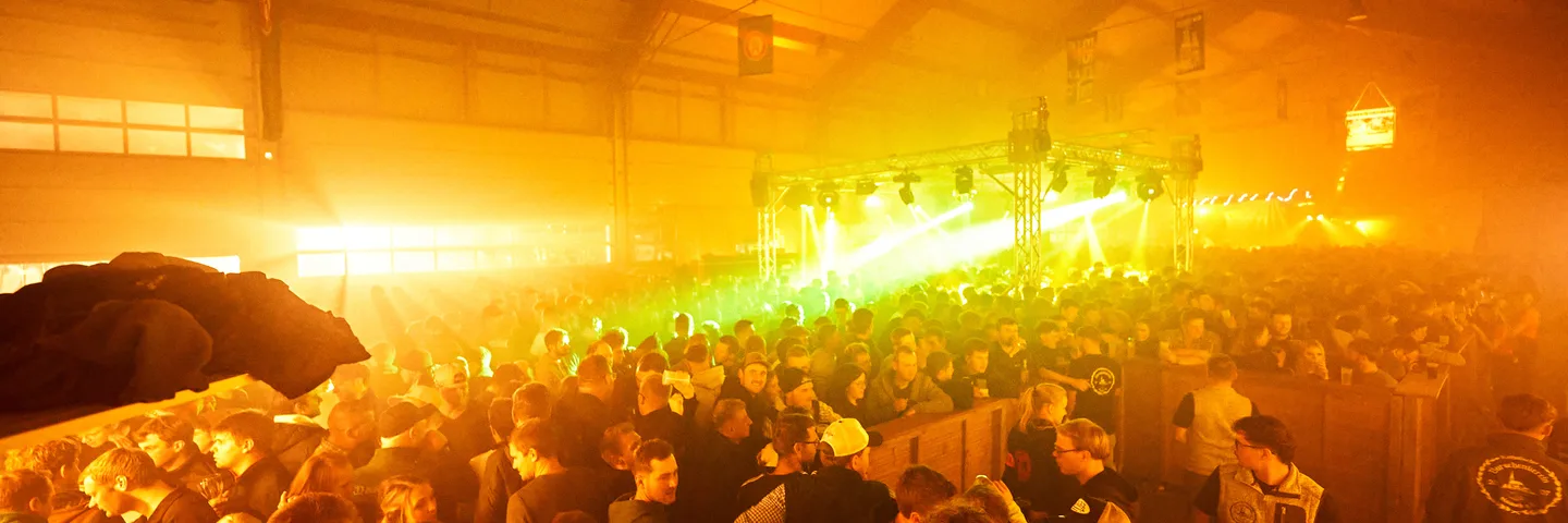 Grüne Laserstrahlen über der dicht gefüllten Tanzfläche in der Halle in Geisberg