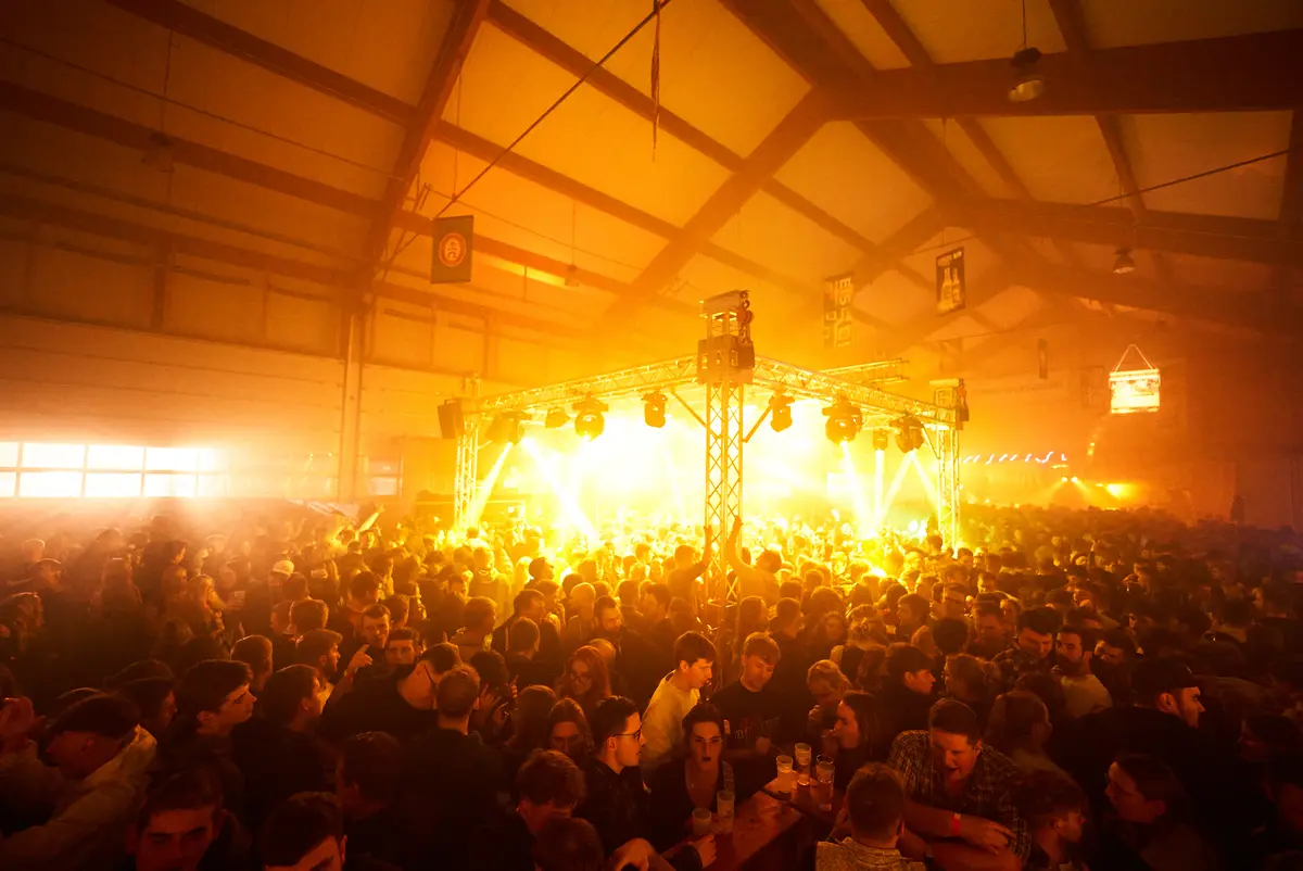 Blick über die volle Halle in Geisberg zur hell beleuchteten Bühne