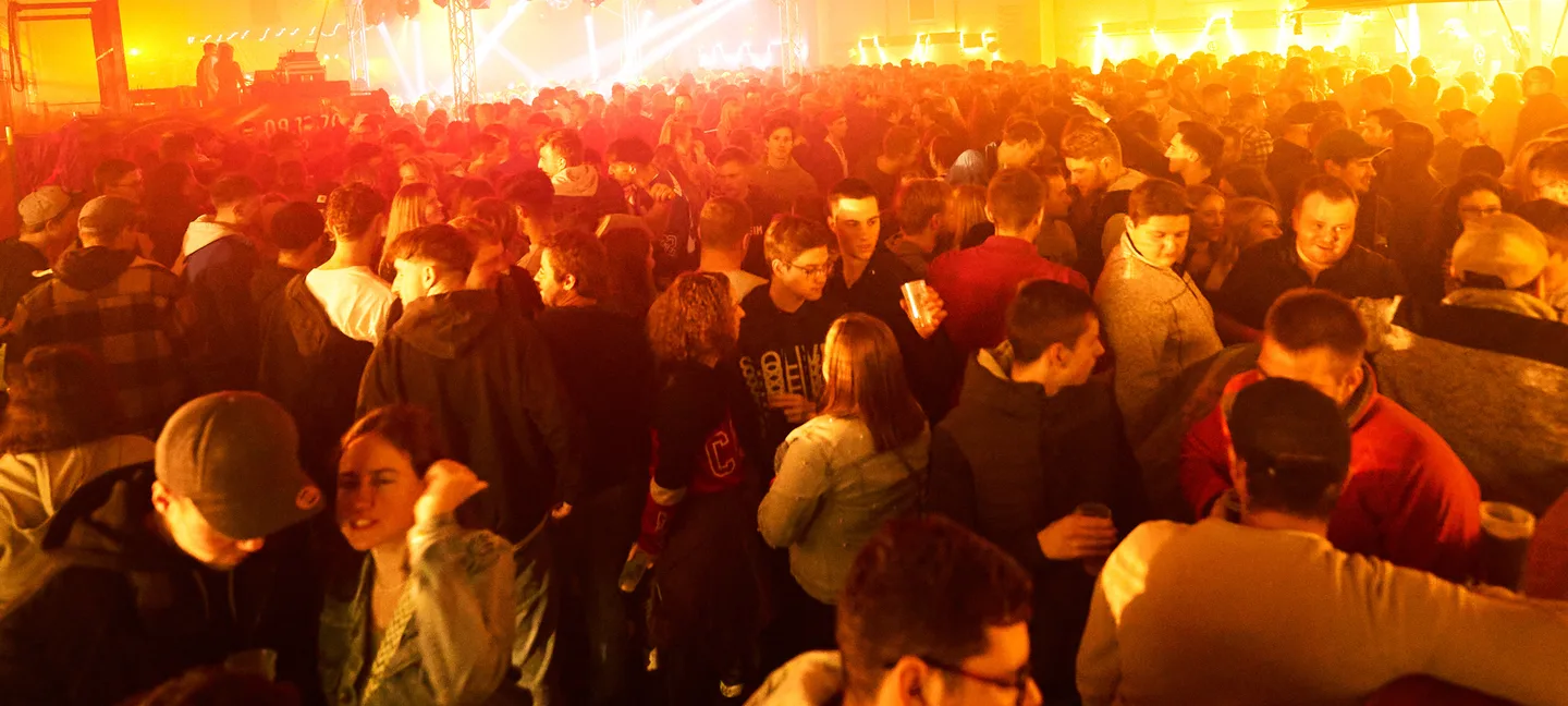 Dicht gefüllte Halle bei der HD-Party in Geisberg, Bühnenlicht über der Menge