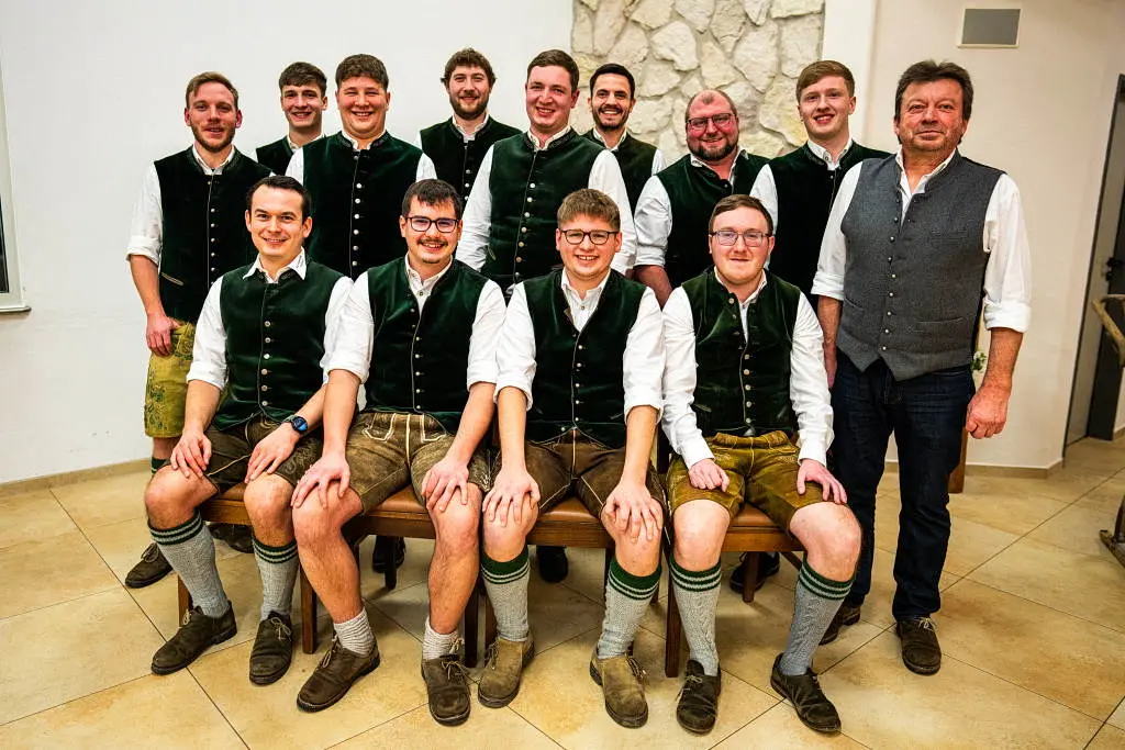 Dreizehn Männer in grüner Vereinstracht und weißem Hemd, vier davon sitzend auf einer Bank, rechts außen der Präses.